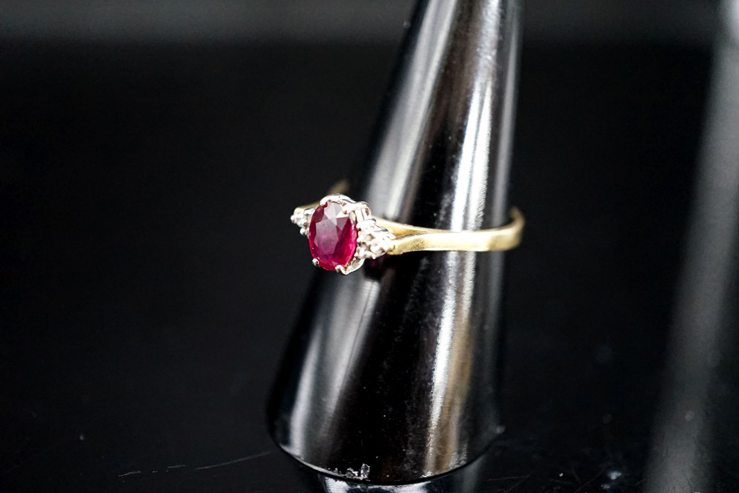 A 750 yellow metal, single stone oval cut ruby and six stone diamond chip set ring, size O, gross weight 2.7 rams.